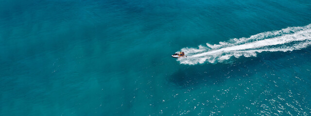 Aerial drone ultra wide photo of jet ski watercraft performing extreme manoeuvres in deep blue bay with calm sea at dusk