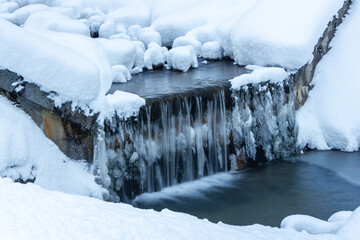 Tranquil mountain creek waterfall surrounded by a frozen landscape in the Austrian alps (Filzmoos, Salzburg county)