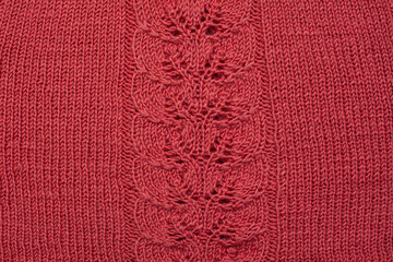 Red knitted cotton fabric, hand knit, plain knitting,  branch in  knitting needles. Horizontal photo