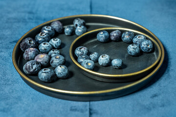 blueberries on dark plates and velvet blue background