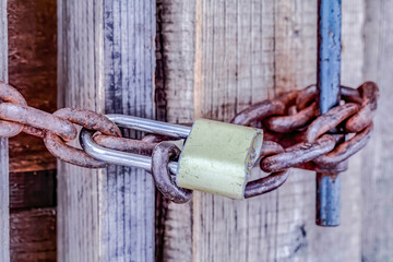 Close up of closed old outdoor bathroom door with padlock and rusty metal chain
