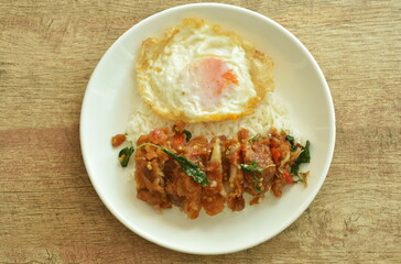 spicy fried crispy chicken with basil leaf and chilli topping egg on rice in plate