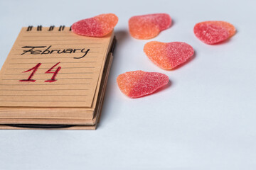 February 14 written in a notebook with gummy hearts on a light blue background