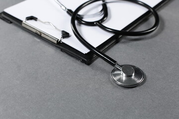 Stethoscope and tablet for recording patients on gray background