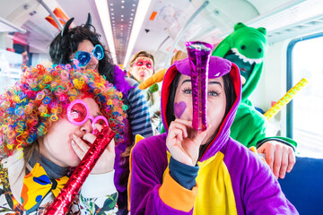 Gruppe Junger Leute fahren mit dem Zug zu karneval party - obrazy, fototapety, plakaty