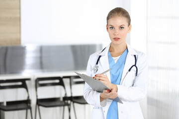 Woman - doctor is using clipboard for filling up medication history record in clinic. Medicine concept