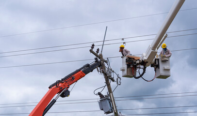 electrician works on bucket car to maintain high voltage transmission lines.