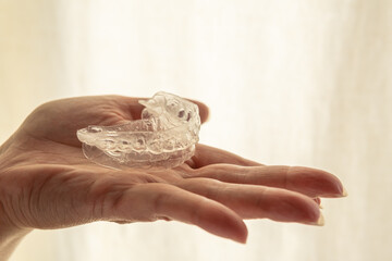 Teeth whitening mold on the palm of one hand