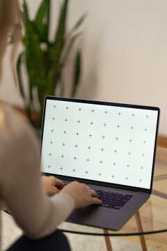 Woman working, laptop in a lap, glass table, browsing computerwith blank screen mock-up for your design at home office with blurry background with free space for custom text about business