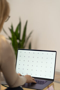 Woman working, laptop in a lap, glass table, browsing computerwith blank screen mock-up for your design at home office with blurry background with free space for custom text about business