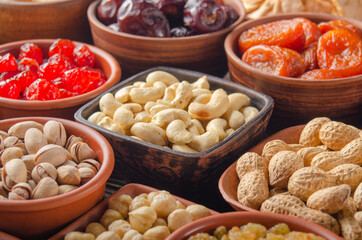 Different nuts and dried fruits in bowls on kitchen table