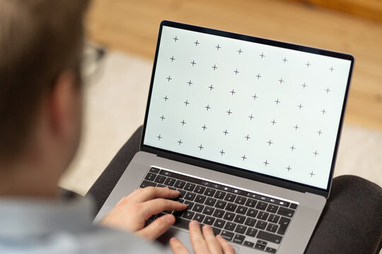 Man with glasses holds laptop in lap, browsing internet or application with blank screen mock-up for your design at home office with blurry background with free space for custom text about business