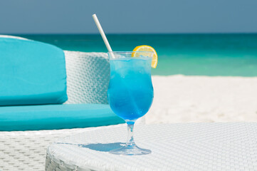 Blue Tropical Cocktails on white rattan table on Background of Warm turquoise ocean. Exotic Summer Vacation.