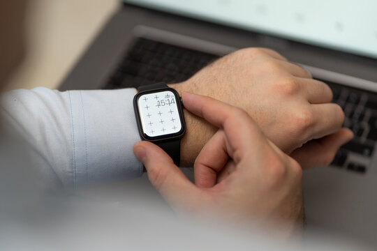 Businessman with smartwatch on hand with blank screen mock-up for your design at home office sitting on the couch with blurry background with free space for custom text