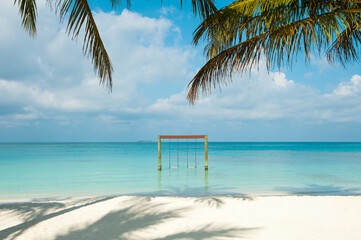 Beautiful view on the beach on Maldive Island. White sand and palm trees and swings in the ocean