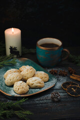 Christmas mood, pastries with coffee and spices, candle and juniper sprigs on an old wooden brown table