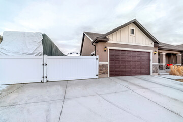 Truck in an open parking area with white gate beside attached garage of house
