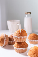 Muffins on table board with cup and bottle of milk. Cupcakes in morning light. Breakfast concept.