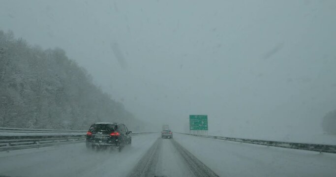 Dashcam dash camera POV slow driving on snowy highway road in Slovenia. Snowstorm in winter season. Snow covering motorway in blizzard. Forward dolly moving, wide angle, real time