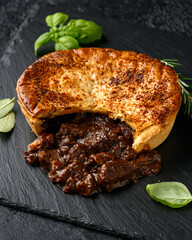 British beef steak pie with onion, wine gravy on rustic stone board
