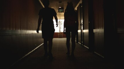 Back view of Caucasian young couple walking hotel hallway