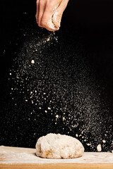 Fototapeta premium Female baker hands making dough for bread with an apron. Natural homemade ingredients. Dark background, brown color grading.
