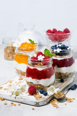 desserts with muesli, berry and fruit puree in jars on white background, vertical
