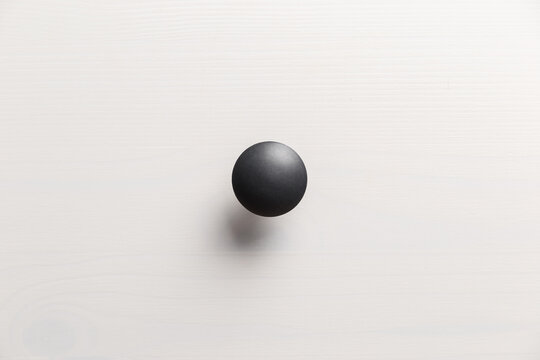 Black handle on white wooden chest of drawers. Minimalism. Minimal concept. Close-up. The texture of natural wood