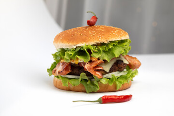 Homemade hamburger with cheese, bacon and chili on white plate