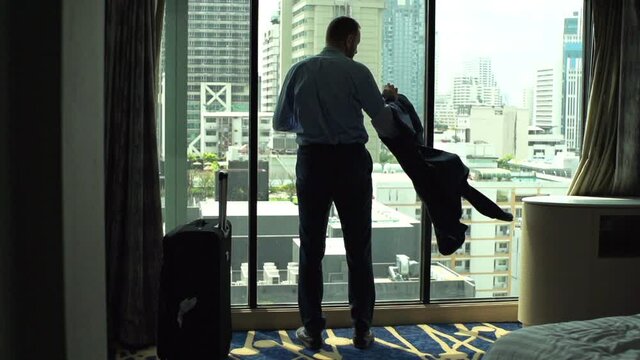 Businessman take off jacket and admire view from window, slow motion