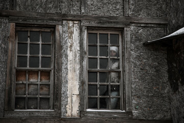 Fototapeta na wymiar The girl stands outside the window in an old abandoned house. Girl in a white jacket. Dilapidated and old window.