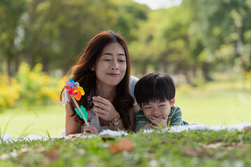 Asian family having fun mother and her son playing windmill in the garden together