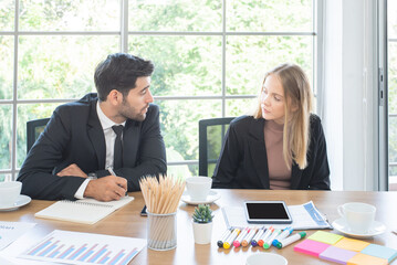 Caucasian businesswoman and  businessman sit at table and talk about business plan in meeting room.