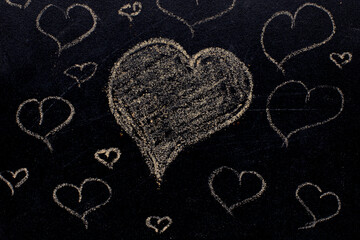 White color chalk hand drawing in heart shape on blackboard background.