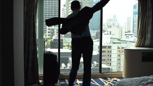 Businessman putting on jacket standing by window at home, super slow motion