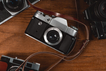 Vintage analog cameras on wooden plank and leather strap
