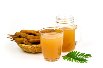 Tamarind juice in glass and tamarind fresh tropical fruit in wicker basket with leaf isolated on white background.