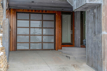 Glass front door and glass paned garage door of home against wood and brick wall