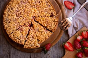 Delicious crumble cake with strawberry on wooden background