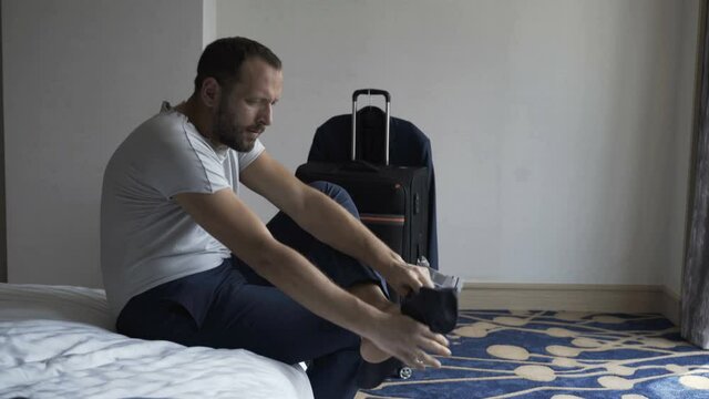 Young businessman wearing socks in bedroom at home