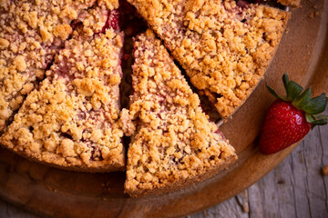 Delicious crumble cake with strawberry on wooden background