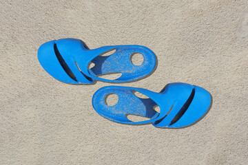 Fototapeta na wymiar Sandals azure old condition and dirty with sand is on beach sand sandy background