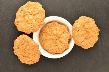Several sweet torchetti cookies with oatmeal, close-up, on a slate board.