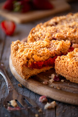 Delicious crumble cake with strawberry on wooden background