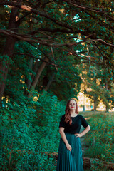 Girl in a turquoise skirt in a fairy forest. Smiling cute girl with red lipstick. Girl on the background of large tree branches