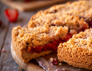 Delicious crumble cake with strawberry on wooden background