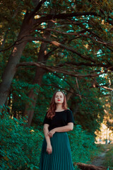Naklejka premium Girl in a turquoise skirt in a fairy forest. Smiling cute girl with red lipstick. Girl on the background of large tree branches