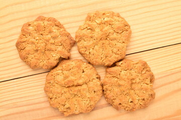 Several sweet torchetti cookies with oatmeal in a bamboo plate, close-up, on a wooden table.