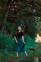 Girl in a turquoise skirt in a fairy forest. Smiling cute girl with red lipstick. Girl on the background of large tree branches