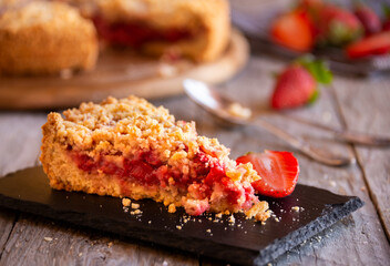Delicious crumble cake with strawberry on wooden background
